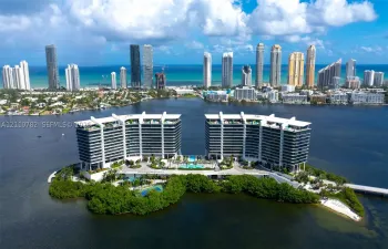 Waterfront high-rise complex situated on a private island, featuring tiered architectural profiles, expansive glass balcony systems, a central outdoor swimming pool, and gated bridge access