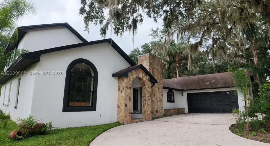 Stucco exterior featuring arched windows, stone masonry accents, and a multi-car garage