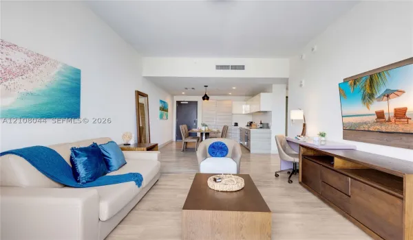 Open-concept interior featuring light wood-finish flooring, recessed lighting, and a modern kitchen with minimalist cabinetry