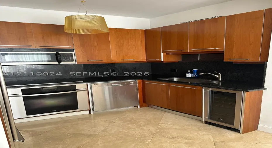 Kitchen featuring cherry-finish cabinetry, dark stone countertops, stainless steel appliances, integrated wine refrigerator, and tile flooring