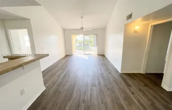 Living area featuring vaulted ceilings, wood-finish flooring, a ceiling fan, a tiled breakfast bar, and sliding glass doors