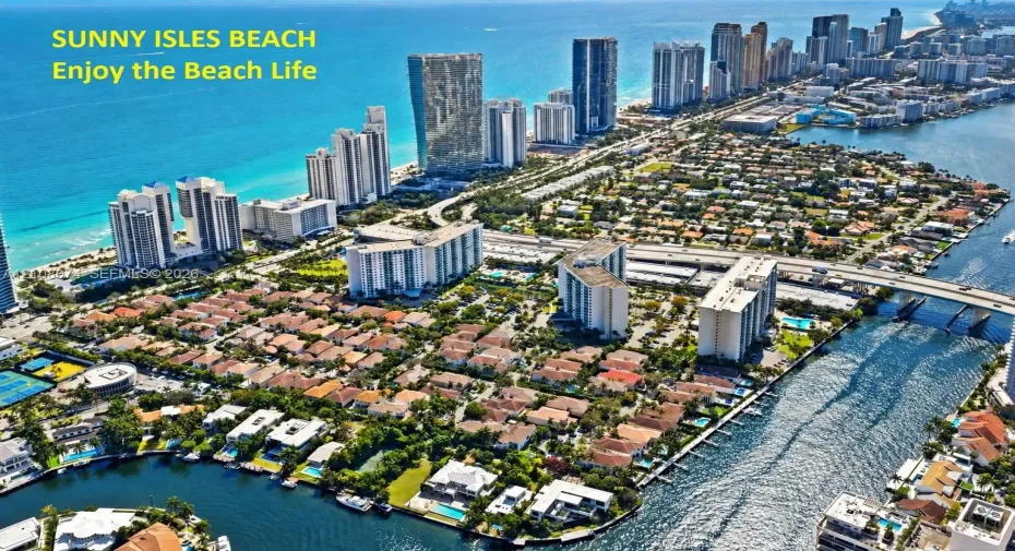 Aerial perspective of Sunny Isles Beach featuring coastal shoreline, high-rise architecture, residential development, inland waterways
