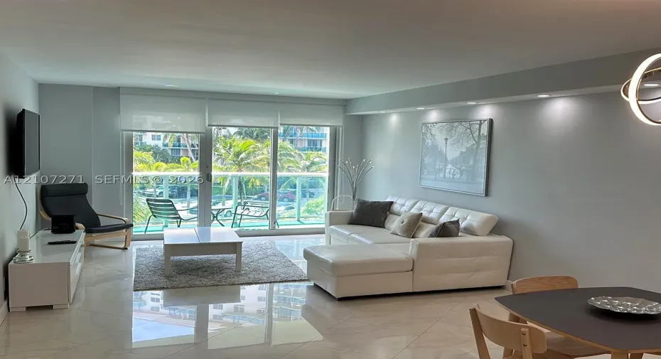 Polished tile flooring, recessed ceiling lighting, and expansive floor-to-ceiling glass doors opening to a balcony