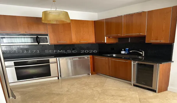 Kitchen featuring cherry-finish cabinetry, dark stone countertops, stainless steel appliances, integrated wine refrigerator, and tile flooring