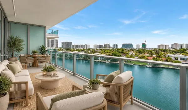 Covered outdoor terrace with glass panel railing, concrete flooring, and water frontage