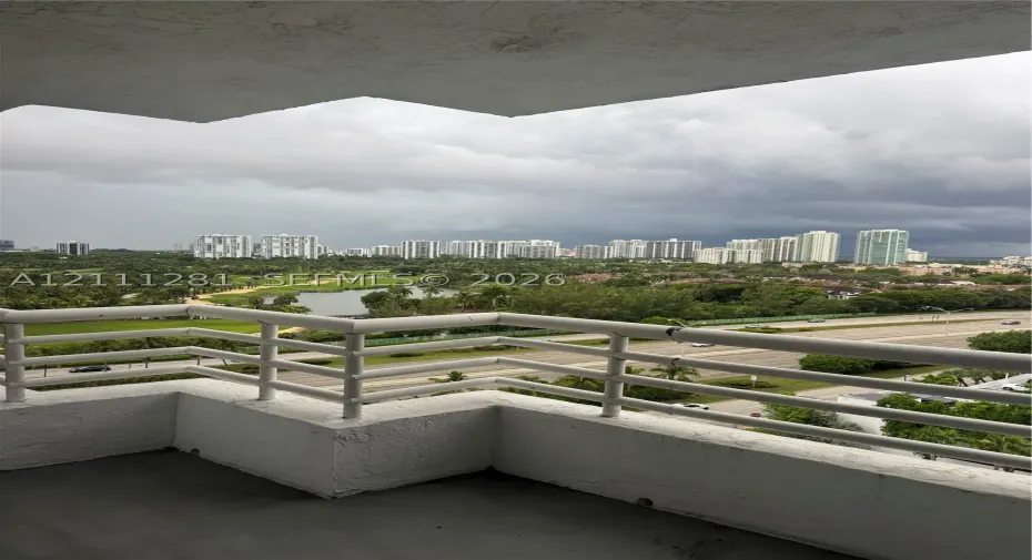 Covered balcony featuring white metal railings and concrete flooring