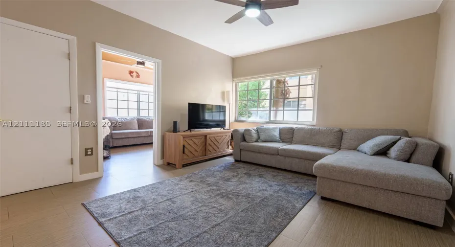 Wood-finish flooring, grid-pattern windows, and ceiling fan with integrated lighting