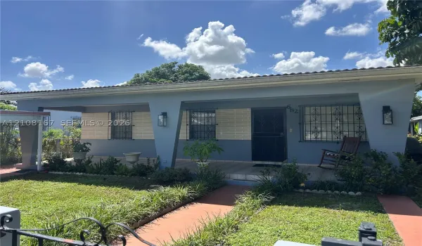 Single-story exterior featuring a covered front porch, decorative metal window security grilles, textured facade detailing, and integrated wall-mounted exterior lighting