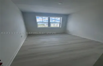 Room featuring light-toned wood-finish flooring, neutral wall paint, and a double-pane window with grid detailing