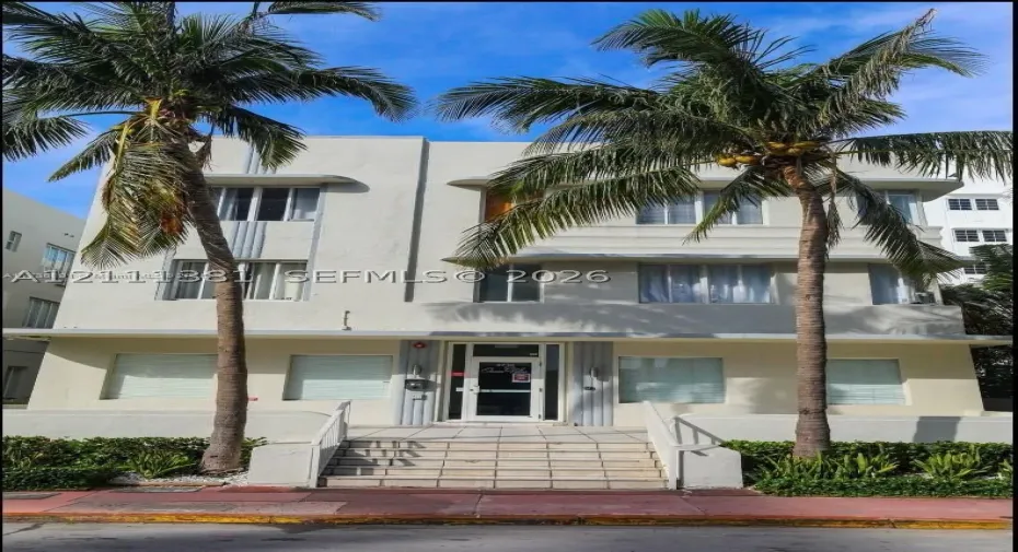 Art Deco exterior featuring a symmetrical facade, concrete-framed windows, vertical decorative fluting, and elevated stone entry stairs