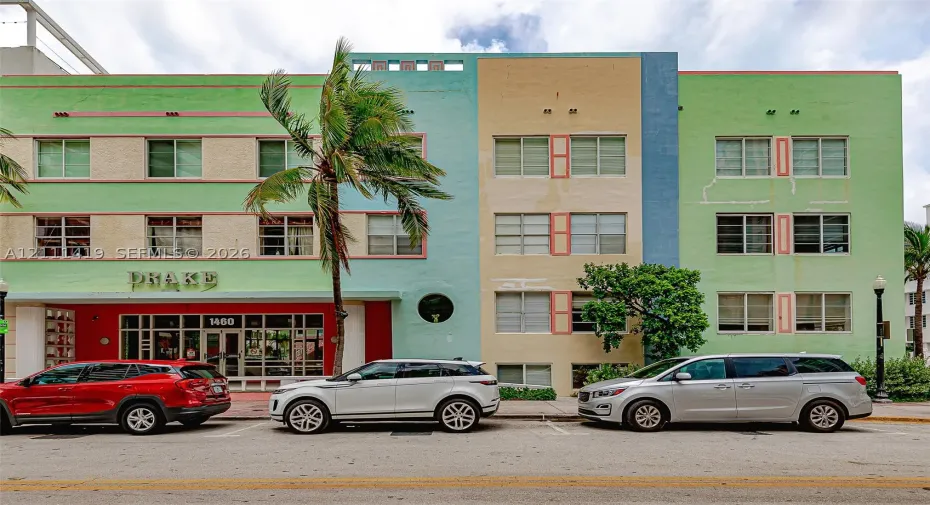 Art Deco exterior featuring a multi-toned pastel facade, inset rectangular windows, circular porthole accent, and prominent geometric roofline detailing