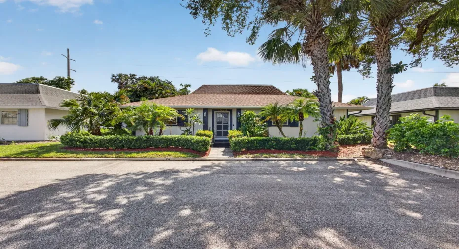 Stand alone, freshly painted, Single Family home, with Manicured landscaping with established hedges, mature palm trees, and a concrete paver walkway leading to the entry
