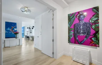 Interior hallway featuring wood-finish flooring, smooth-finish walls, ceiling-mounted circular lighting, and a full-height interior door with metal hinges