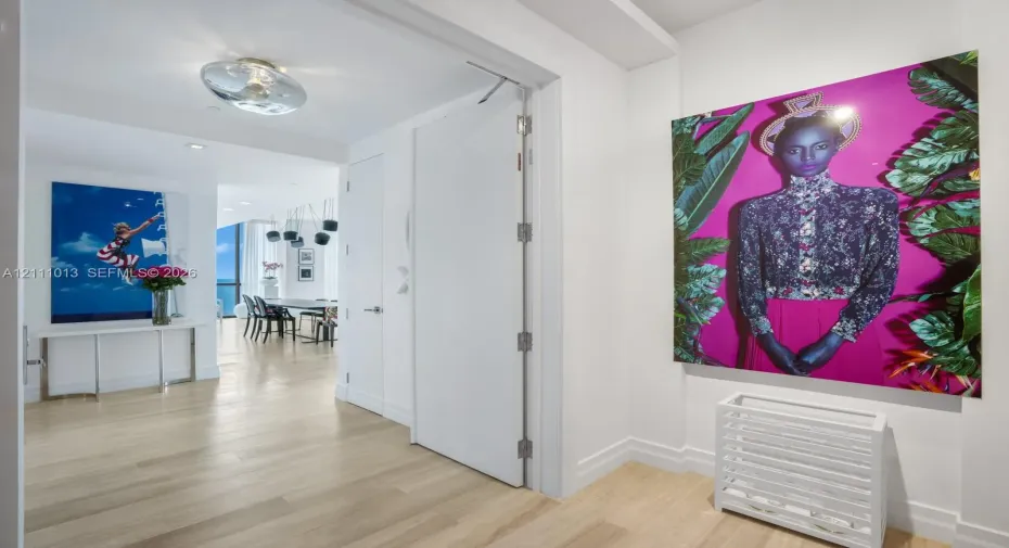 Interior hallway featuring wood-finish flooring, smooth-finish walls, ceiling-mounted circular lighting, and a full-height interior door with metal hinges