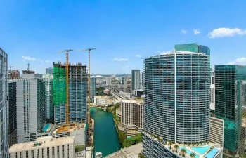 High-rise urban landscape featuring a waterway, multi-story glass-facade towers, and structured infrastructure