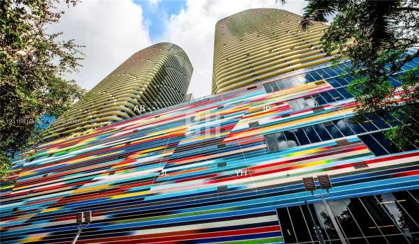 High-rise towers featuring undulating concrete balconies and a multi-colored, linear-patterned facade with glass window wall panels