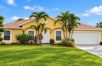 window trim, and a manicured lawn with mature palm landscaping