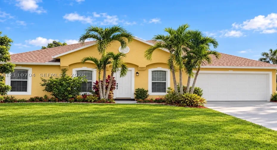 window trim, and a manicured lawn with mature palm landscaping