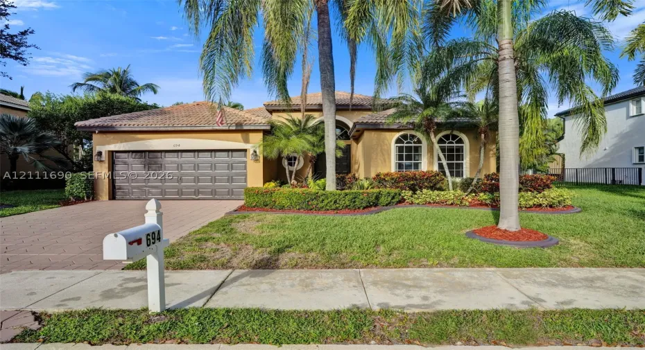 Single-story exterior featuring a tile roof, stucco finish, arched windows, and a paved driveway leading to a two-car garage