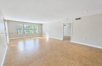 Spacious room featuring neutral wall tones, large-format tile flooring, recessed ceiling lighting, and multiple windows
