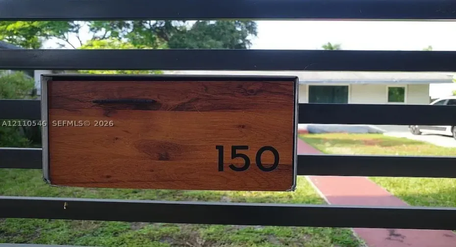 Horizontal metal slat privacy gate featuring a wood-finish address plaque with numeric detailing