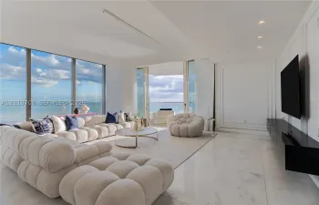 Floor-to-ceiling windows, polished stone flooring, recessed ceiling lighting, wall panel molding, and sliding glass doors to the exterior
