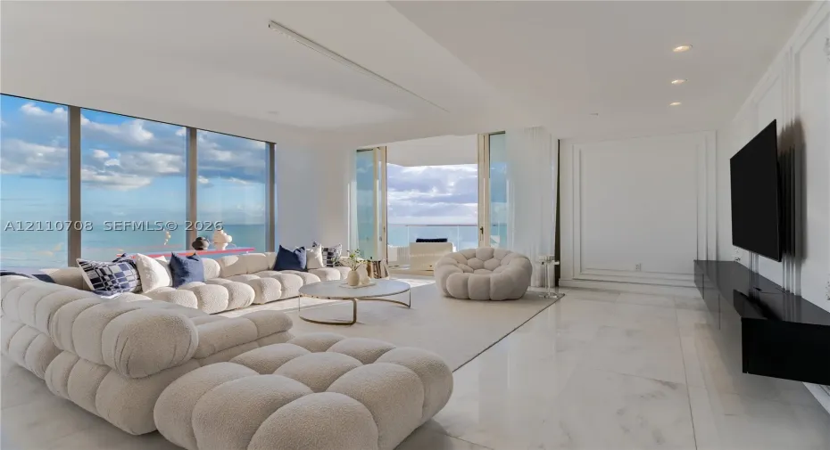 Floor-to-ceiling windows, polished stone flooring, recessed ceiling lighting, wall panel molding, and sliding glass doors to the exterior