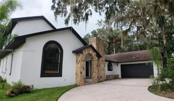 Stucco exterior featuring arched windows, stone masonry accents, and a multi-car garage