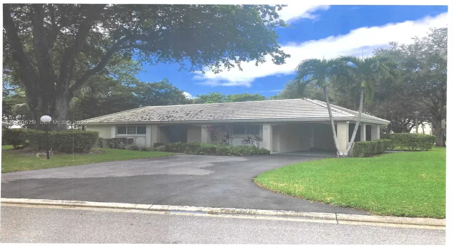 Single-story exterior featuring a gabled roofline, covered entryway, manicured lawn, paved driveway, and mature landscaping