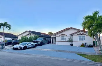 Single-story residence featuring a stucco exterior, multi-pane windows, a tiled roof, and a paved concrete driveway