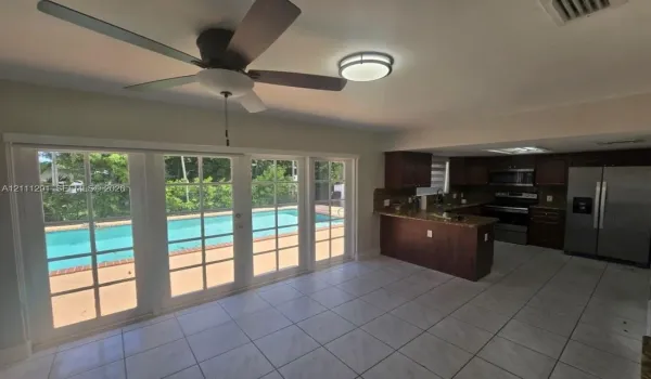 Kitchen featuring dark cabinetry, stone countertops, and stainless steel appliances, paired with a multi-pane glass door system opening to a swimming pool