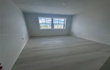 Room featuring light-toned wood-finish flooring, neutral wall paint, and a double-pane window with grid detailing
