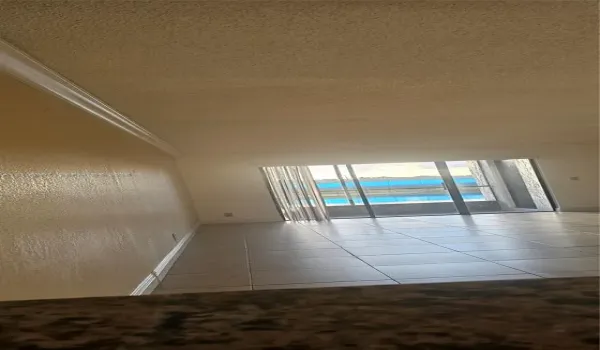 Interior space featuring neutral-toned tile flooring, textured ceiling, crown molding, and sliding glass doors leading to a balcony