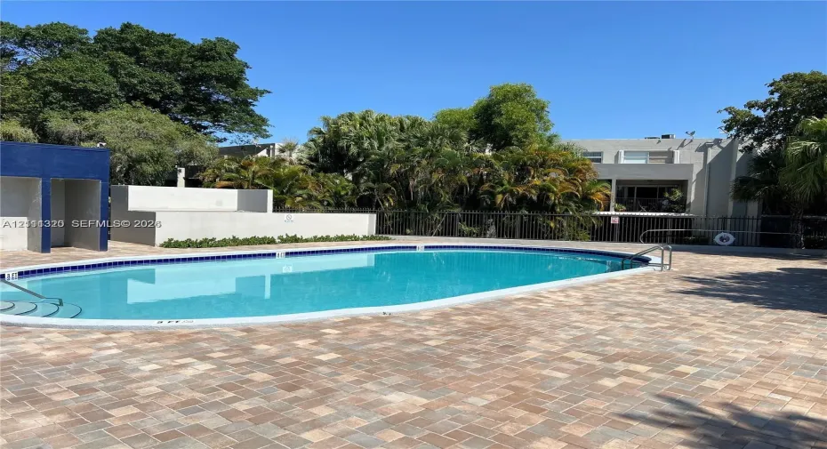 Oval swimming pool with tile border, paver deck, and privacy wall