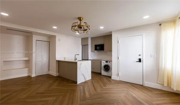 Herringbone wood-finish flooring, kitchen island with stone-finish waterfall countertop, built-in cabinetry, recessed lighting, and ornate metallic chandelier