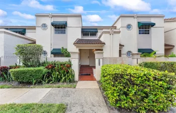 Stucco exterior featuring decorative octagonal windows, arched entryway with brick-style flooring, and green fabric awnings