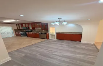 Kitchen featuring wood-finish cabinetry, stone countertops, a multi-light chandelier, a built-in arched display niche, and a combination of tile and wood-finish flooring