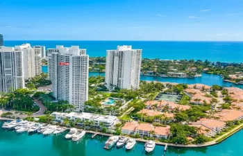 Aerial coastal perspective featuring high-rise towers, private marina slips, and proximity to the open ocean
