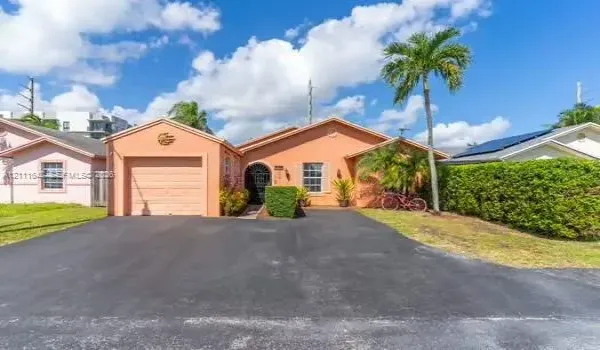 Single-story residence featuring a stucco exterior, attached one-car garage, asphalt driveway, arched entryway with wrought-iron security gate, and manicured shrubbery