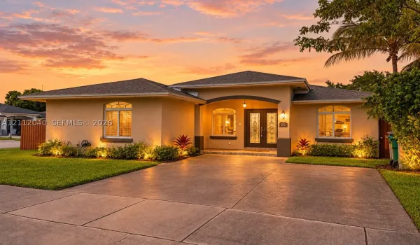 Stucco exterior residence featuring an arched covered entryway, double glass-panel front doors, a concrete driveway, and a shingle roof