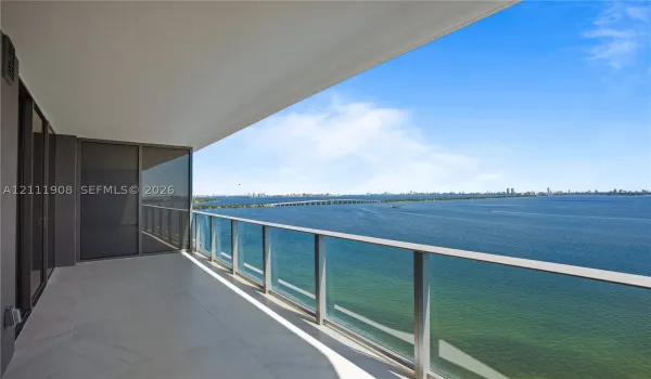 Covered balcony featuring expansive stone tile flooring and floor-to-ceiling glass panel railings