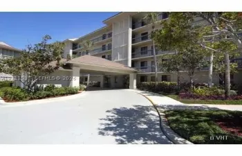 Multi-story building exterior featuring a covered porte-cochère, paved driveway, private balconies, and landscaped grounds