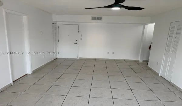Neutral-toned tile flooring, three-blade ceiling fan with integrated light fixture, and multiple louvered-style closet doors