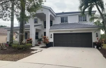 Two-story residence featuring a tile roof, stucco exterior, covered entryway, and a two-car garage