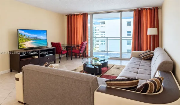 Living space featuring large-format ceramic tile flooring, floor-to-ceiling glass sliding doors, and a private balcony with metal railing