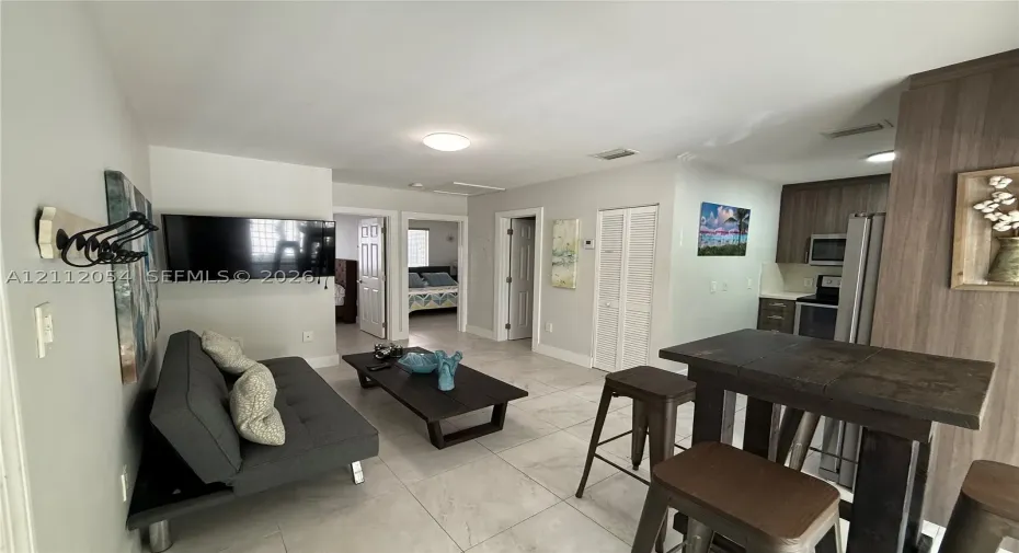 Open floor plan featuring large-format tile flooring, kitchen with built-in cabinetry, and integrated appliances