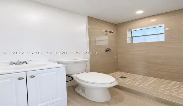 Bathroom featuring a white vanity cabinet with a integrated sink, two-piece toilet, and walk-in shower with large-format wall tile, mosaic tile flooring, and recessed lighting