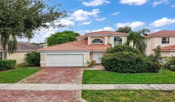 Two-story residence featuring a terracotta-tiled roof, double-door entryway, arched windows, and a paved driveway
