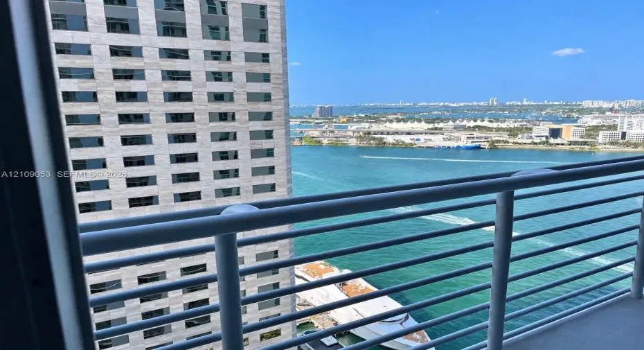 Elevated balcony featuring a metal railing with a clear horizon line encompassing the waterfront, harbor, and urban skyline