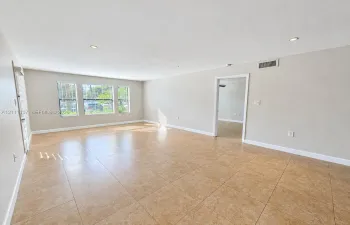 Spacious room featuring neutral wall tones, large-format tile flooring, recessed ceiling lighting, and multiple windows